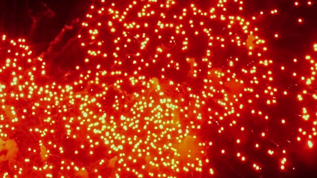 Thousands of bright embers ascend into the night sky. Glowing, fiery sparks float upward during an outdoor celebration in Fairhaven, Massachusetts, during a festive Autumn evening.