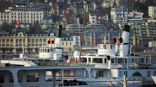 LUCERNE, SWITZERLAND - MARCH 06 2026: Panning shot across the historic paddle steamers docked at the pier with the Casino Luzern building in the background on Lake Lucerne.