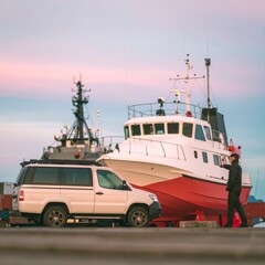 Naklejka premium man inspecting military ship beside parked van at naval dockyard