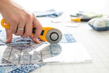 Cutting blue patterned fabric with a rotary cutter and clear acrylic ruler