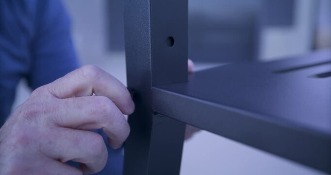 Grown man's hand twisting screw into hole in metal object