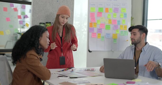 Diverse group of startup team engaging in brainstorming session, using sticky notes on glass wall to organize ideas, plan next steps. Creativity and collaborative spirit of modern entrepreneurial team