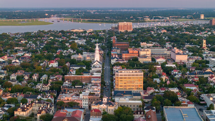 Naklejka premium Aerial View of Broad Street in downtown Charleston, South Carolina cityscape landscape showcasing city streets, historic churches and building during morning sunrise light with boat harbor in distance