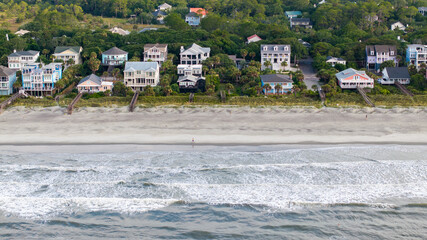 Naklejka premium Aerial view of waterfront mansion homes in Folly Beach near Charleston, South Carolina landscapes with person runnning along beach and waves during morning light