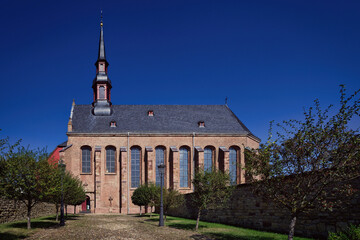 Stunning brick facade of St. Nikolaus Church in Fuessenich, Zülpich. Sacral architecture with iconic ridge turret against a clear blue summer sky © gehapromo