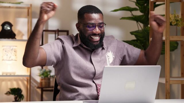 Excited happy African man with his laptop celebrating an online win, job offer, or personal achievement