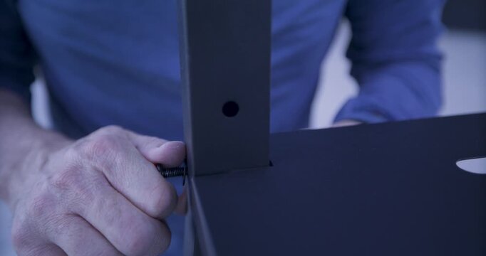 Man's hand attempting to twist screw into metal bar and platform - closeup