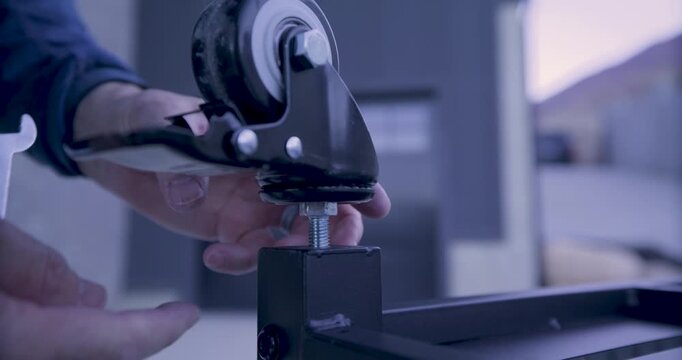 Wheel being screwed onto metal bar of object - closeup