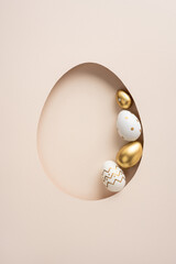 Fototapeta premium Minimal vertical Happy Easter greeting featuring a golden and white decorated egg tucked into an egg-shaped paper cutout evoking elegant spring celebration and luxury seasonal decor