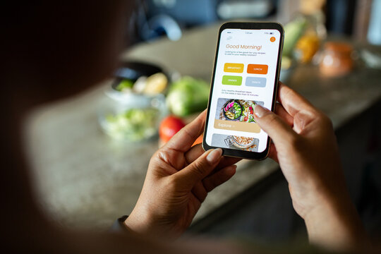 Person browsing healthy recipes on smartphone in kitchen
