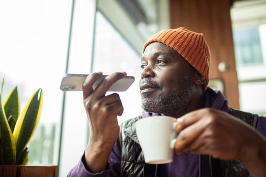 Man using voice assistant on smartphone at cafe