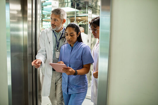 Medical team reviewing tablet in hospital elevator