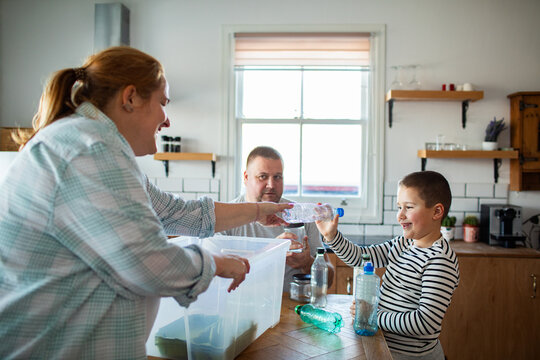 Family recycling plastic bottles together in home kitchen