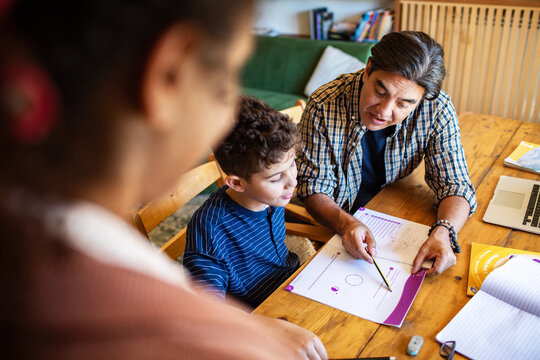 Parent helping child with math homework at kitchen table