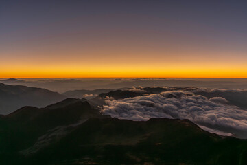 Fototapeta premium Sunrise landscape at Jiaozi Snow Mountain in Kunming, Yunnan, China, featuring dramatic cliffs, a mountain boardwalk, and a sea of clouds below. High-altitude scenic viewpoint bathed in warm morning l