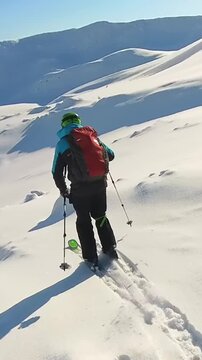 A Person Enjoys Fresh Powder While Freeride Skiing Down a Vast, Snowy Mountain on a Bright Winter Day