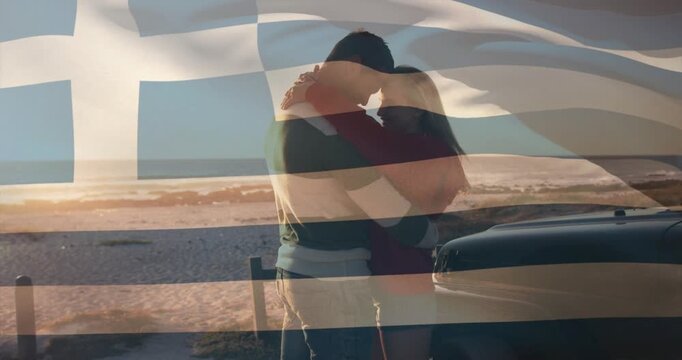 Couple facing closing in hugging by car sunset kissing lovingly tour Greek flag waving across frame
