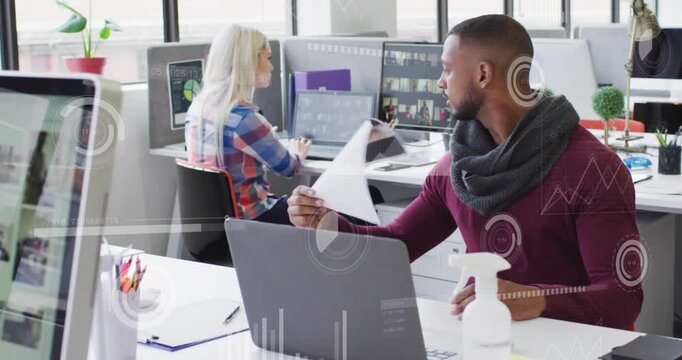Man reviewing pages and handing print to woman at desks in office, requesting design feedback