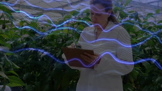 Woman in coat taking sensor reading tilting clipboard and logging crop data while waveform passing