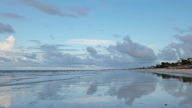 A dramatic partly cloudy sky mirrored perfectly in wet sand and turquoise shallows at Jericoacoara Beach, Northeast Brazil