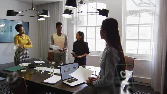 4 women team papers tablets in business meeting laptop showing charts starting AR icons deciding