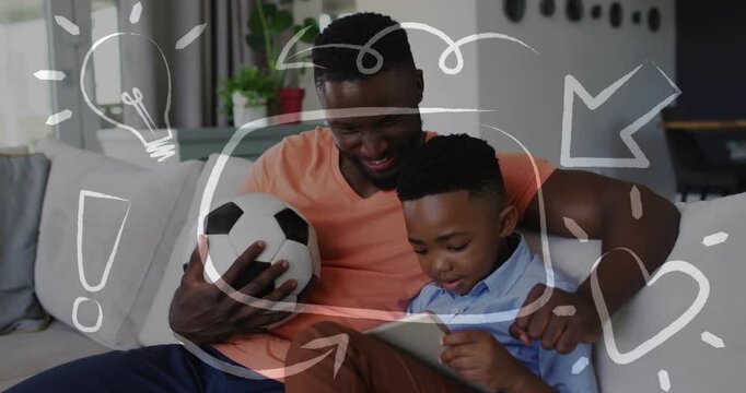 Dad guiding son sofa pointing tablet causing doodles son tapping soccer ball seen for education