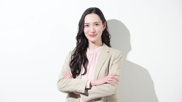 かわいいスーツの日本人女性のカメラ目線の笑顔　多幸感や成功や自信あふれる春色ビジネスイメージのスローモーション動画　転職や採用