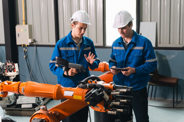 Engineers inspecting industrial robot arm in factory automation technology innovation smart...