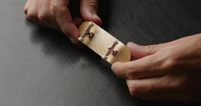 Small wooden fingerboard skateboard in hands.  Close-up.
