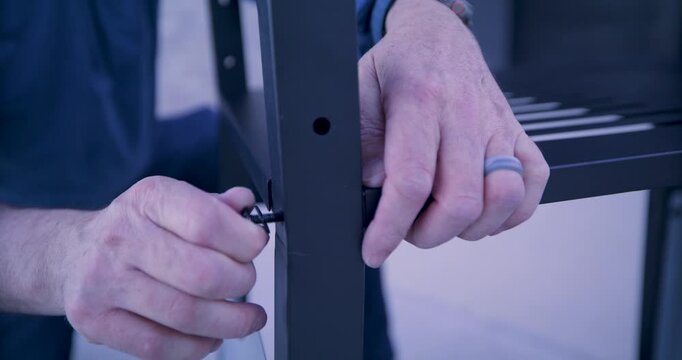 Close up of person's hands putting screw into hole of metal cart