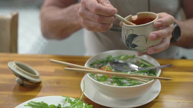 Traditional Vietnamese Beef Noodle Soup Garnished With Fresh Herbs And Serving Tools. Flavorful Bowl Of Vietnamese Beef Pho Garnished Generously With Herbs And Accompanied By Utensils For Eating