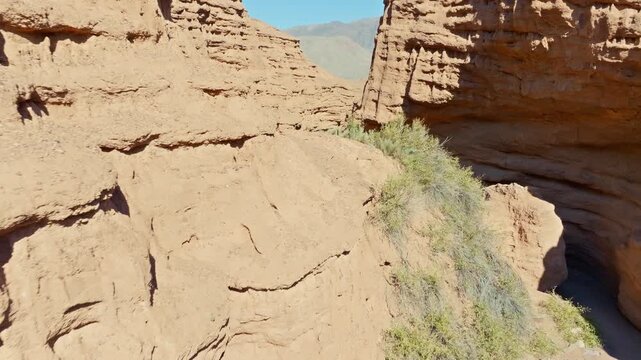 Low altitude drone fly over narrow eroded sandstone zigzagging canyon in Kyrgyzstan desert