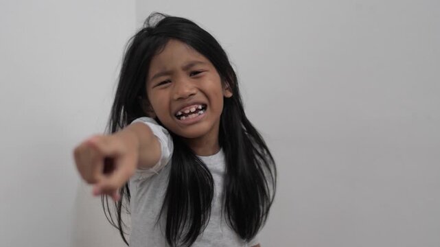 Angry little Asian girl with furious face expression, unhappy child looking at camera with grumpy and mad emotion, childhood behavior and anger management