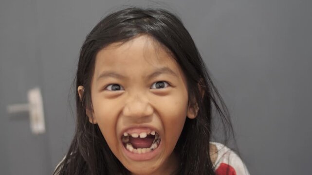 Little Asian girl shouting loudly and screaming with angry expression, child tantrum, frustrated and disappointed childhood