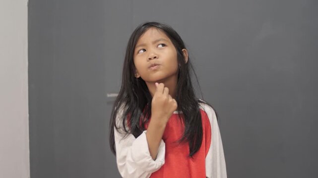 Cheerful little Asian girl pointing up with an "Aha" moment expression, happy child having a great idea or finding a solution, inspiration, creativity, and early education