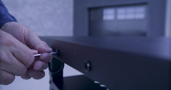 Man's hands using tool to tighten three screws into metal platform - closeup