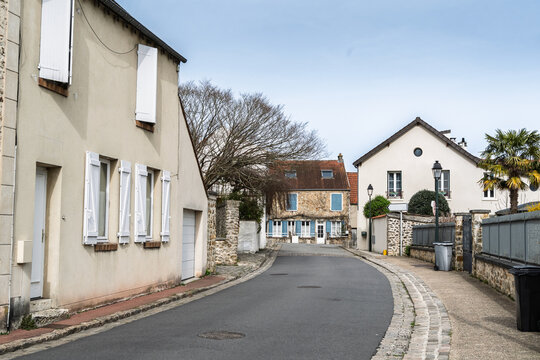 Quiet residential street in Vieux Montigny, the historic core of Montigny le Bretonneux in Saint Quentin en Yvelines, France, showing traditional french village houses, shutters and stone walls.