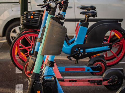 Close view of electric scooters and electric bicycles from share riding services in France, parked in an urban setting, reflecting micromobility, app based rental transport and low emission travel.