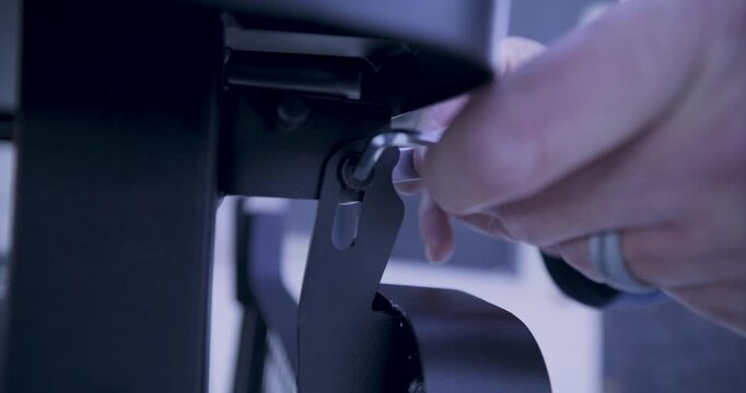 Man's hand using tools to screw screws into metal object - closeup