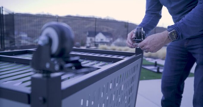 Steady cam, rack focus shot of wheels on upside down cart and man attaching another