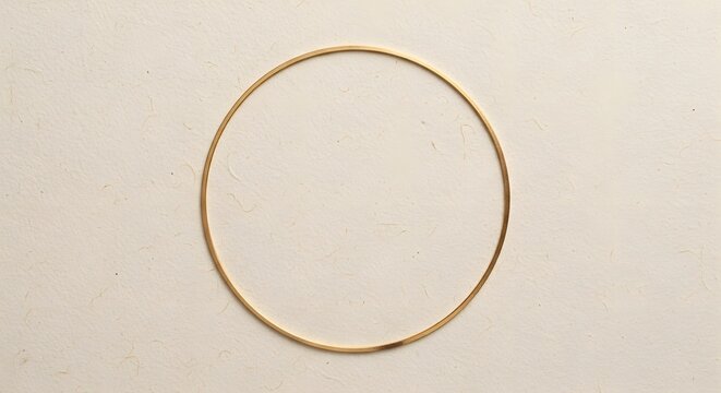 A single thin golden circle ring placed centrally on a textured off-white handmade paper surface