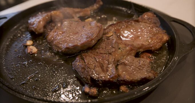 Delicious, sizzling steak on pan - closeup, steady cam movement 