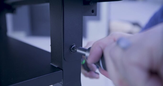 Man quickly turning screw driver on screw on metal leg of grill