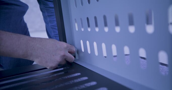 Man using small tool to screw in a screw into metal structure