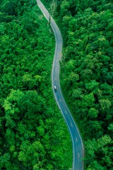 Fototapete Grün Aerial forest road with car creating abstract background for electric vehicle, ESG, sustainability and green investment business concepts.  © Hand Robot