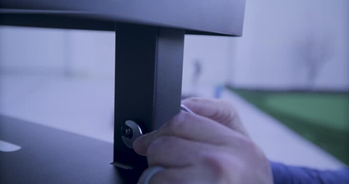 Close up of man's hand using tiny wrench on small bolt of metal cart