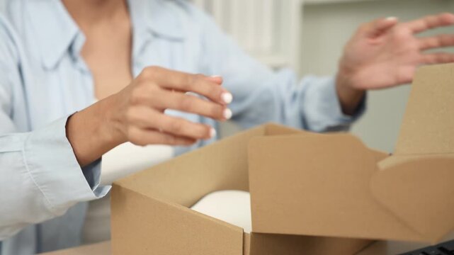 Ecommerce packing shipping fulfillment order small business owner smiling while sealing cardboard parcel box with tape preparing shipment delivery for online store customers from home workspace