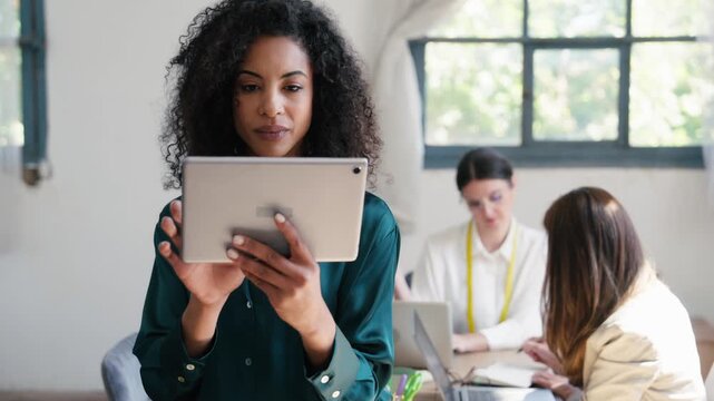 Video of fashion designer using digital tablet whileher colleagues working together in a coworking place