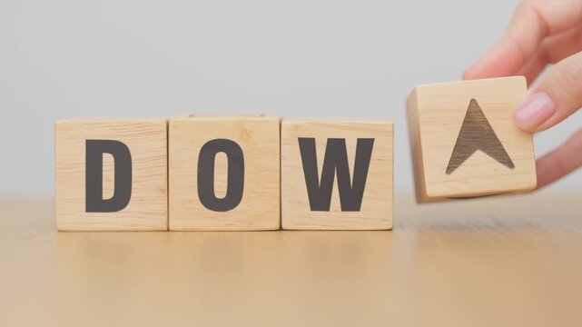 Hand change wooden block of Dow Jones Index text to UP and Down arrow symbol icon. stock market index, trade, trade company in the United States, financial growth and Cut loss concept