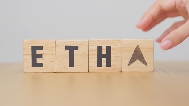 Hand change Wooden block with ETH or Ethereum text to UP and Down arrow symbol. cryptocurrency, blockchain, price, down and up, decrease and increase, cut loss, trade and financial concepts